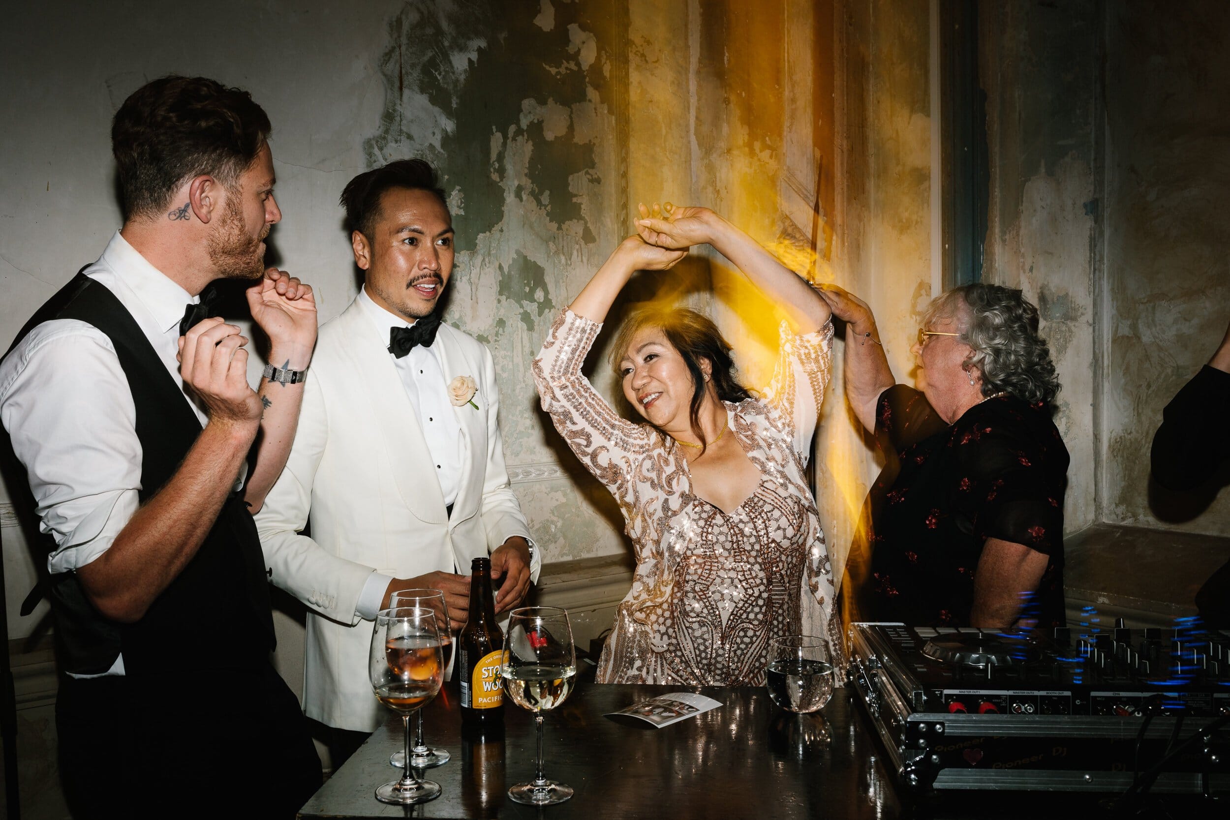 Same Sex Wedding Couple With Family Dancing Alongside DJ