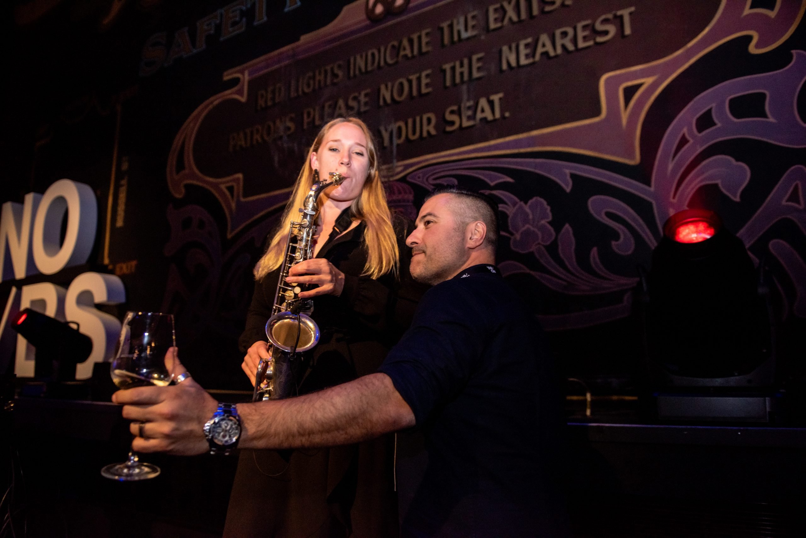 Female Sax Player With Guest With Wine In His Hand At Melbourne Conference Event